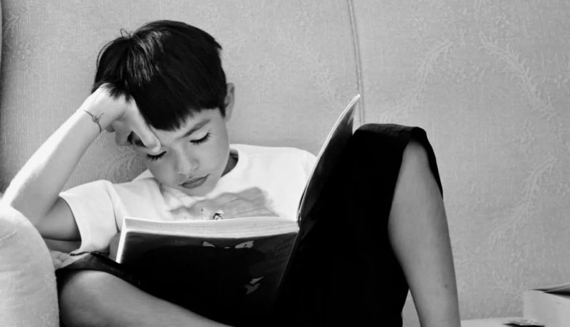 Dzieci w szkole czytają książki. Na zdjęciu dziecko chętnie czyta książkę.